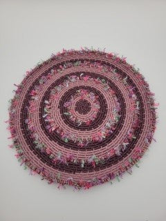 Handmade coiled yarn table centre in pink and soft purple with green highlights