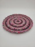 Handmade coiled yarn table centre in pink and soft purple with green highlights