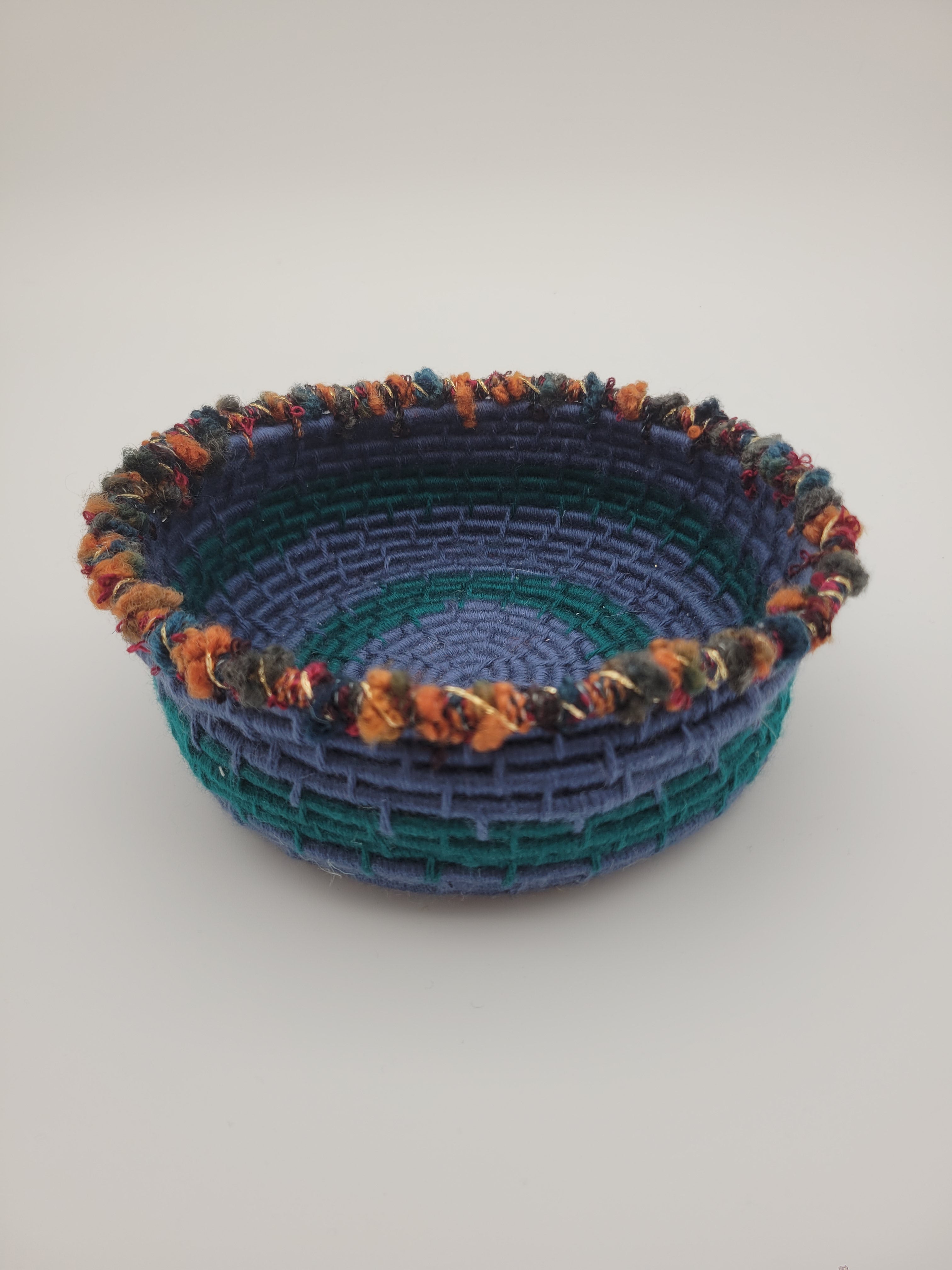 Handmade coiled yarn bowl in blue and green with orange and red details